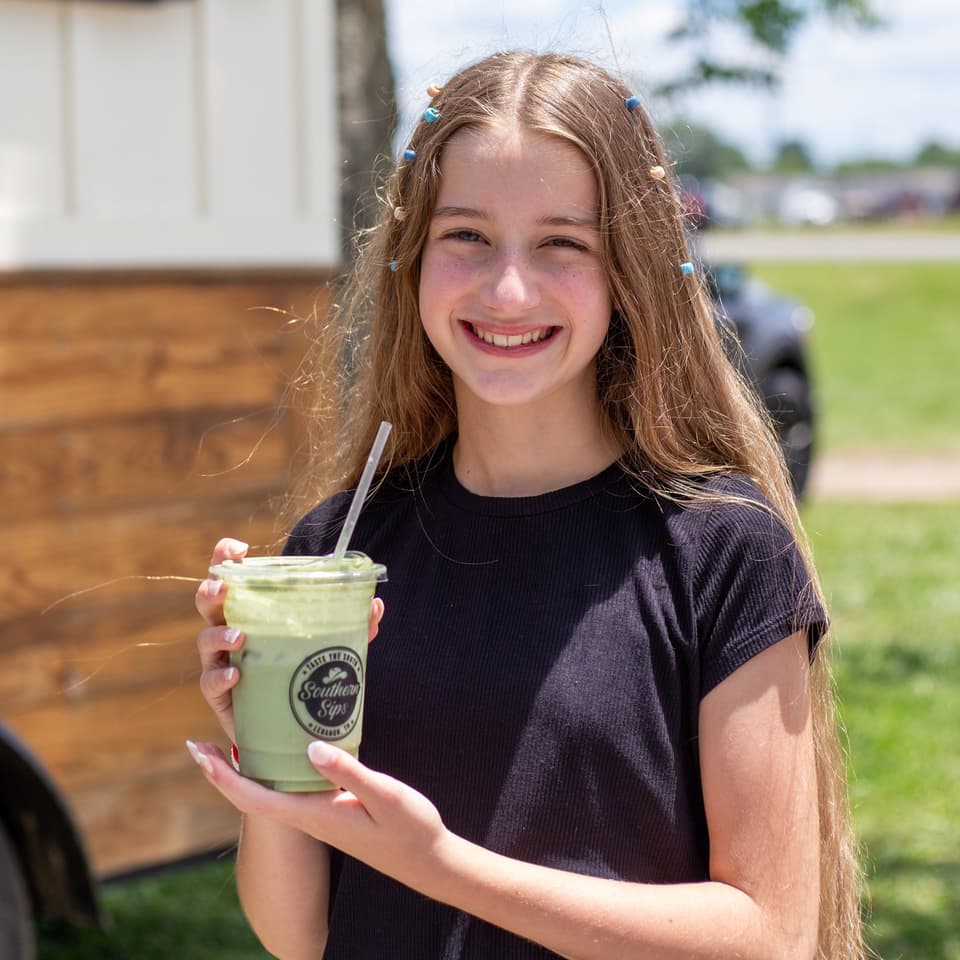 Young guest smiling with a green Southern Sips drink