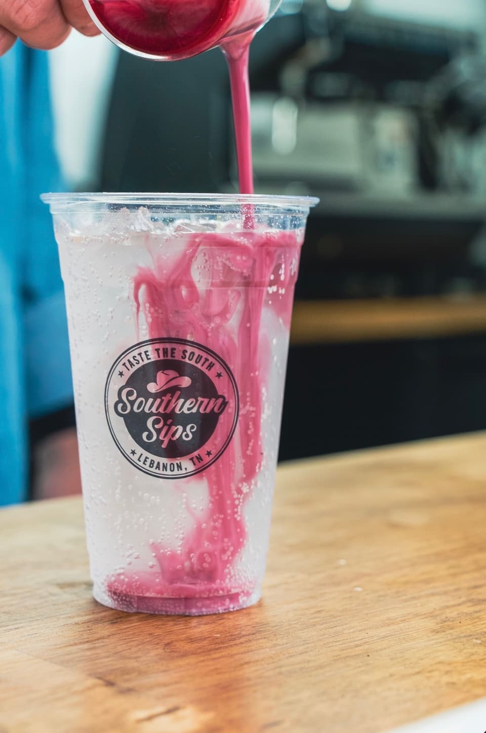 Bright pink syrup being poured into a Southern Sips cup
