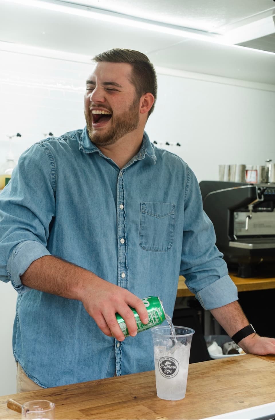 Team member laughing while pouring a drink behind the bar